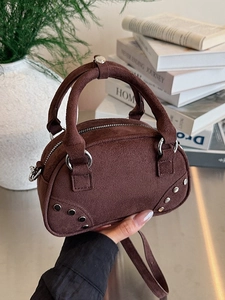 Brown suede minimalist handbag with silver studs and a curved bowling bag shape