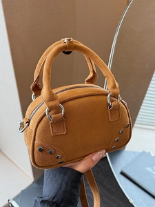Brown suede half-moon handbag with silver studs and top handles in a lifestyle setting