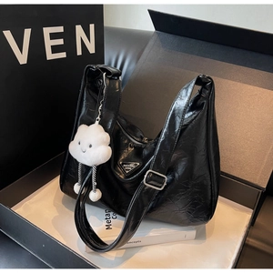 Détail du sac cabas froncé noir avec logo argenté et breloque peluche nuage en coffret cadeau