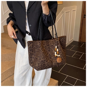 Dettaglio della borsa tote leopardata con ciondolo di perline e tracolla in pelle nera