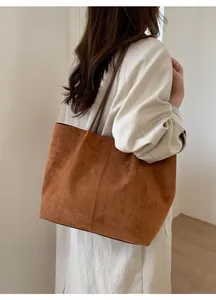 Close-up of caramel suede tote bag with vertical stitching shown on a model's shoulder