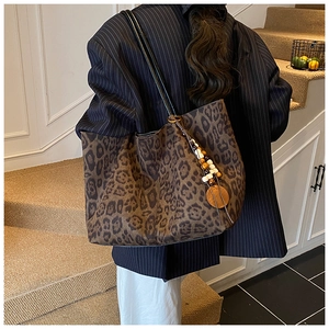 Dettaglio della borsa tote leopardata con ciondolo di perline sulla spalla del modello