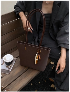 Dettaglio della borsa tote in pelle marrone scuro con ciondolo di perline colorate sul manico