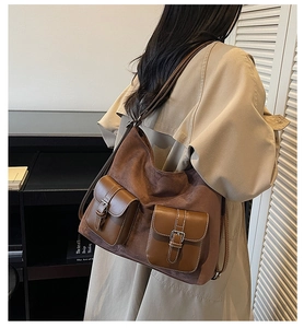 Detail of vintage brown suede tote bag with leather pockets and silver metal buckles