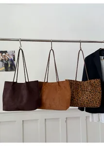 Three oversized suede tote bags in brown, caramel, and leopard print shown on a rack