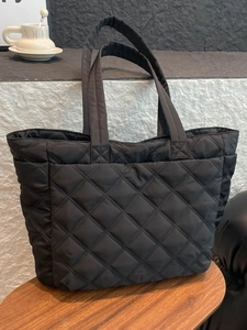 Quilted black nylon tote bag with rhombus pattern on a wooden bench for daily travel