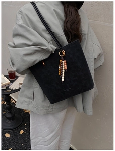 Dettaglio della borsa tote nera minimalista con nappa di perline colorate in stile bohémien