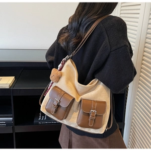 Detail of vintage tote bag featuring brown leather pockets and a cute bear charm accessory