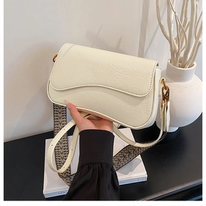 Détail du sac bandoulière crème avec rabat ondulé et sangle à motif ethnique