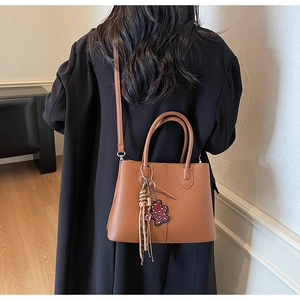 Detailed view of brown lychee grain tote bag with adjustable strap and bear charm