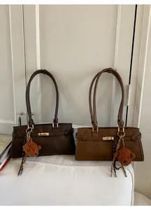 Detail of vintage underarm bags in brown and caramel with golden locks and plush charms