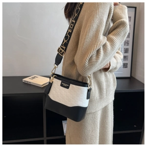 On-body view of a black and white checkerboard bucket bag with stylish wide woven strap