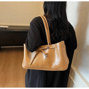 Close-up of caramel leather tote bag with stylish metal belt buckle detail