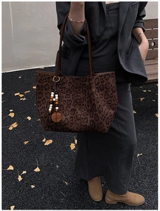 Dettaglio borsa tote leopardata con ciondolo in legno e tracolla marrone all'aperto