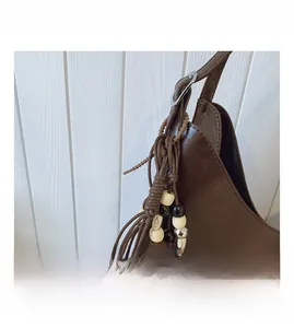 Gros plan d'un sac cabas vintage marron avec perles tissées et breloque à pompon