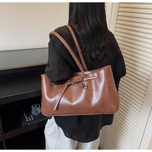 Detail of vintage dark brown tote bag with metal buckle strap on polished leather finish
