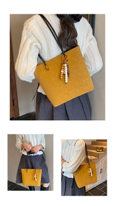 Dettaglio della borsa tote giallo senape vintage con ciondolo in legno e tracolle