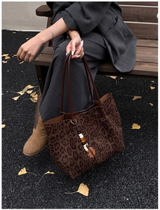 Borsa tote leopardata con ciondolo in perline di legno su una panca di legno autunnale