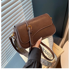 Détail du sac à bandoulière en cuir café avec boucle bronze et sangle tissée colorée
