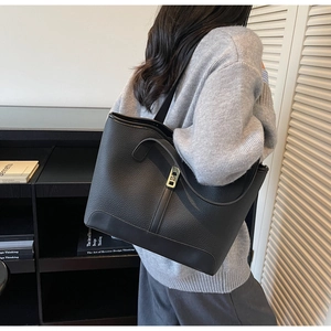 Close-up of black leather tote bag with lychee texture and gold buckle decoration