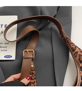 Detail of leopard print tote bag featuring leather strap and golden metal buckle adjustment