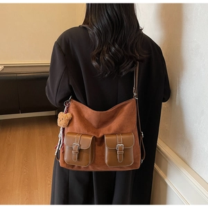 Brown vintage suede tote bag with dual front pockets and plush bear charm on model
