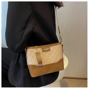 Detail of checkered fabric and brown leather hobo bag with metal chain strap