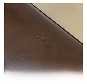 Détail macro de la texture cuir marron foncé avec logo embossé sur le sac cabas