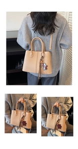 Detail of lychee pattern leather texture on tote bag with cute bear charm and tassel