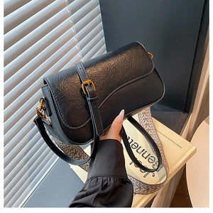 Détail d'un sac rétro noir en similicuir avec boucles dorées et bandoulière tissée