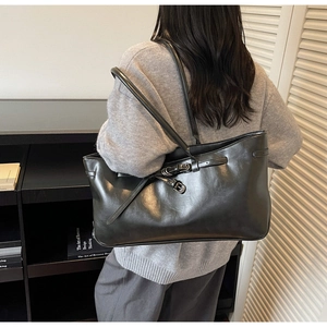 Detail of glossy black PU leather tote bag with dual adjustable buckle straps