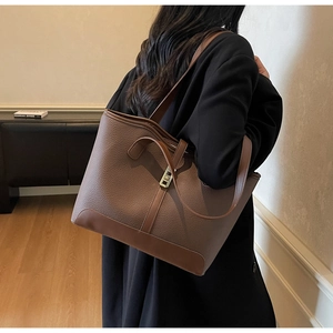 Detail of brown leather tote bag with lychee grain texture and light gold metal lock