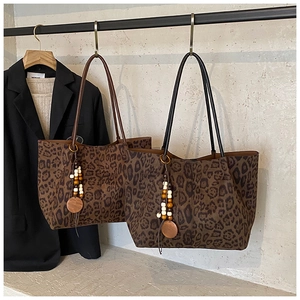 Dettaglio di borse tote leopardate con ciondoli di perline e texture scamosciata premium