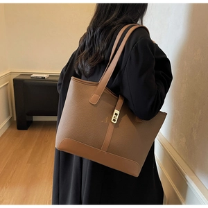 Brown lychee grain tote bag with magnetic closure shown on shoulder in lifestyle setting