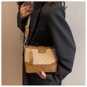 Detail of checkered hobo bag with wide shoulder strap worn over a black winter coat