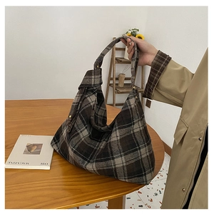 Detail of checkered wool tote bag showing thick texture and metal buckle on wide strap