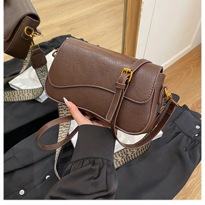 Détail d'un sac selle marron avec rabat vague et double bandoulière en vue miroir style