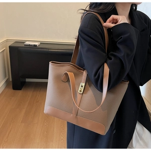Detail of caramel brown tote bag featuring lychee grain leather and gold metal lock
