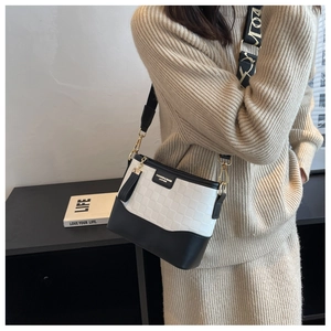 Detail of checkered embossed bicolor handbag with adjustable jacquard strap and leather tassel