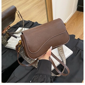 Détail du sac vintage marron foncé avec rabat ondulé et bandoulière tissée à motifs