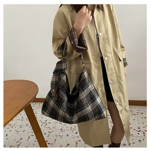 Close-up of retro plaid wool tote bag styled with khaki trench coat for autumn fashion
