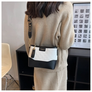 Detail of crossbody bag featuring plaid textures and stylish jacquard wide strap