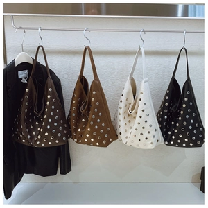 Détail de quatre sacs cabas cloutés en cuir marron foncé, caramel, blanc et noir