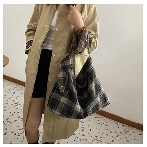 Close-up of contrast wool plaid tote bag with wide strap and retro metal buckle details