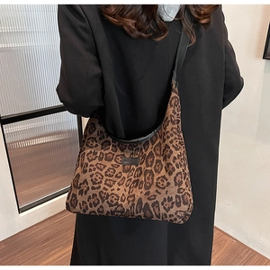 Dettaglio della borsa tote leopardata con cinturini in pelle nera e patch logo del marchio