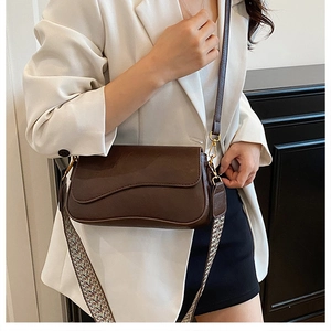 Détail d'un sac bandoulière en cuir marron avec sangle jacquard colorée et fermoir doré