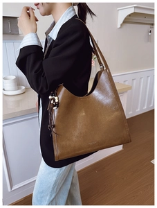Detail of vintage brown tote bag with glossy leather texture and wooden bead tassel