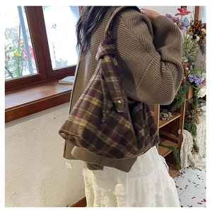 Detail of vintage plaid tote bag made of thick wool fabric with metallic lock and soft drapes