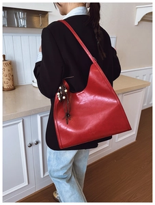 Detail of red oil wax leather tote bag with bohemian beaded tassel and logo embossing