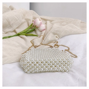 Detail of white handmade pearl beaded handbag with elegant gold metal handle and chain strap